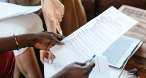 Pessoas reunidas em volta de documento o apreciando