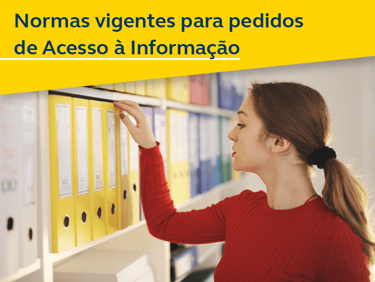 Normas vigentes para pedidos de Acesso à informação. Mulher branca, com roupa vermelha, frente a uma estante com vários livros e pastas , procurando algo.