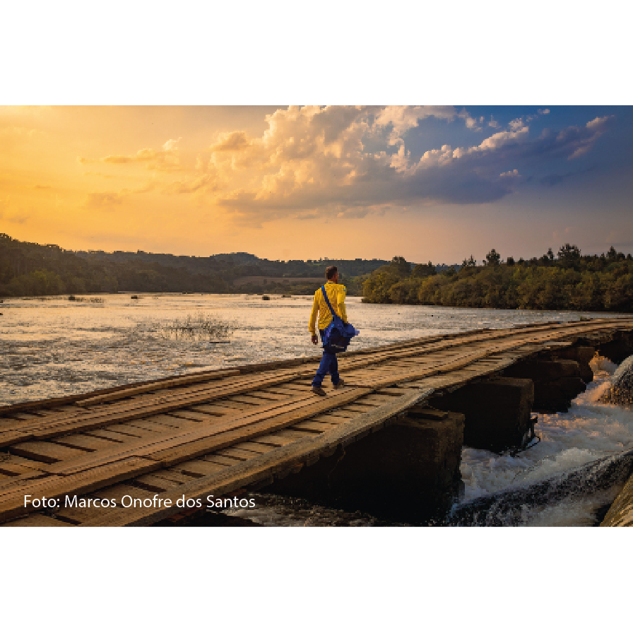 Carteiro andando por uma ponte de madeira, ao fundo um rio