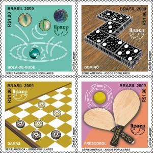 imagem de 4 selos formando uma quadra sobre jogos: gude, dominó, tabuleiro e raquetes de madeira.
