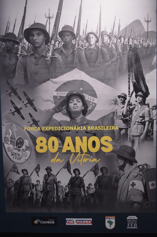 Exposição Comemorativa da Força Expedicionária Brasileira de “80 Anos da Vitória”. O Cartaz apresenta fundo escuro com imagens de vários soldados armados, uma bandeira do Brasil no centro e o seguinte texto: Força Expedicionária Brasileira 80 Anos da Vitória.