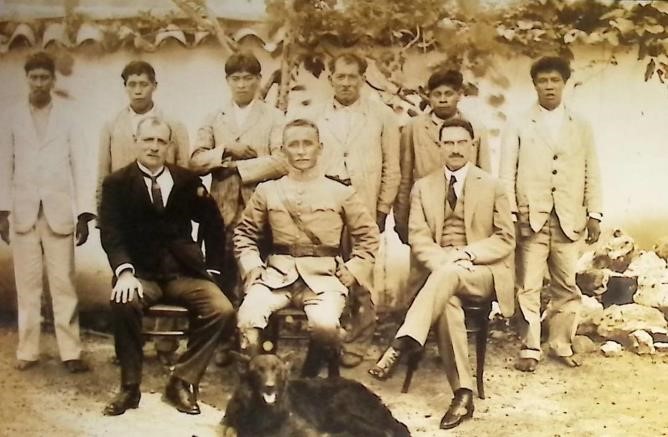 Integração e proteção aos indígenas Foto de homens à frente de um muro. Três deles estão sentados à frente, outros cinco em pé.