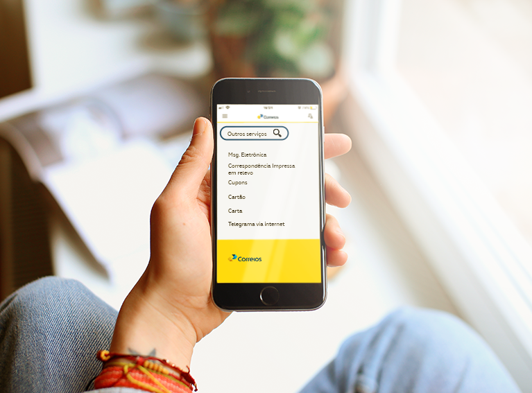 Outros serviços internacionais Mão segurando celular. Em sua tela o aplicativo dos Correios.