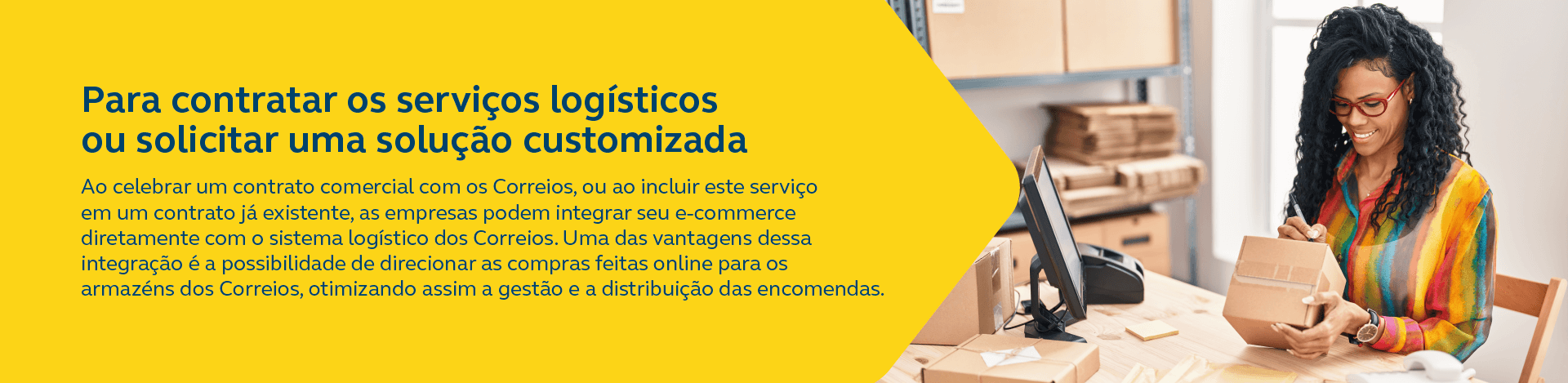 Imagem de mulher com blusa colorida, sentada em frente a uma mesa escrevendo em uma caixa